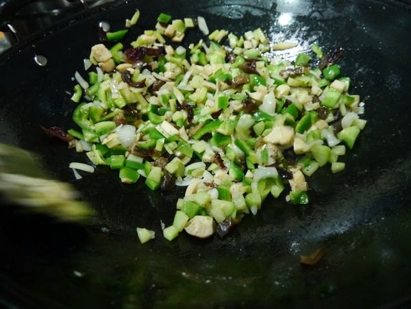 依序下佛手瓜丁、木耳、杏香菇拌炒，炒軟之後加入青椒丁灑上[調味料]拌炒均勻