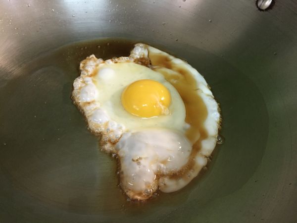 炒鍋洗淨，另下一大匙麻油熱鍋後，打一個蛋，煎至半熟。同時間另起一爐，將水燒開後，放入適量麵線煮約2-3分鐘後撈起備用。