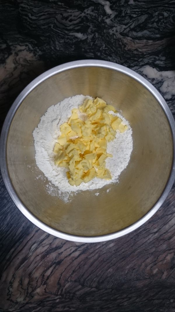 將中筋麵粉過篩在鋼盆內，加入切小丁的無鹽奶油