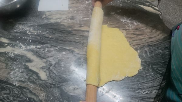 將派皮麵團用擀麵棍由左至右捲起，請勿用手直接鏟起麵團，以免麵團斷裂