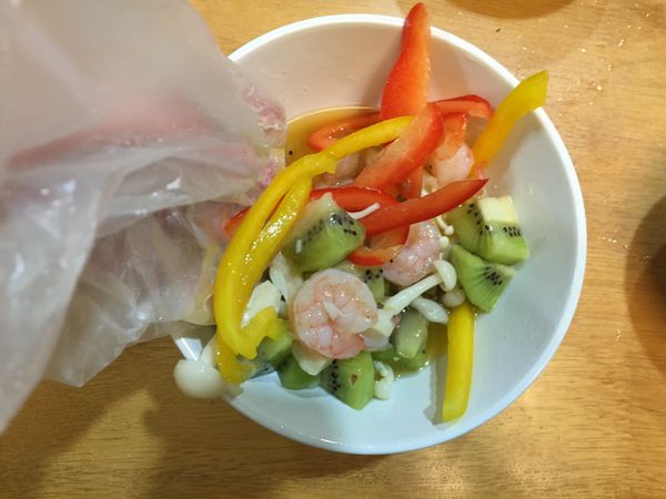 將處理好備用的彩椒、蝦仁、雪白菇、奇異果置入同一容器，並倒入製作好的橙醬，抓勻使食材平均沾上醬汁。