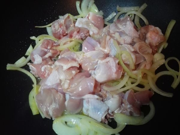 放入用鹽、米酒醃漬20分鐘的雞腿肉塊，充分拌勻炒香。