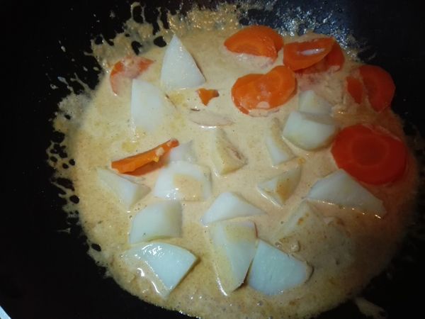 放入蒸熟的紅蘿蔔與馬鈴薯塊，拌炒均勻。