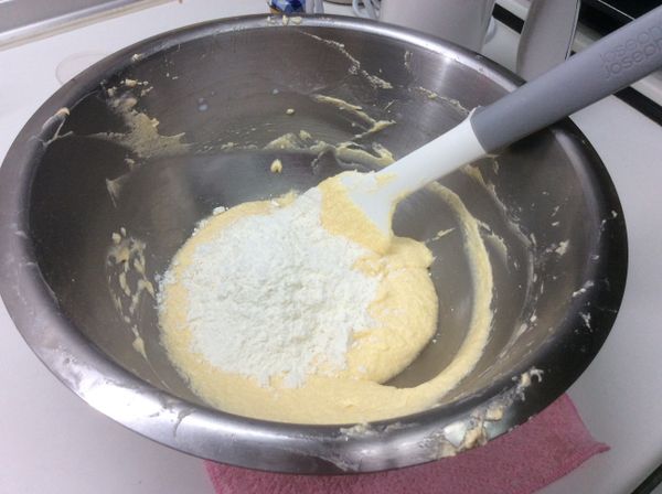 低筋麵粉和泡打粉混勻後過篩，分兩次倒入奶油糊中。先倒一半麵粉拌勻，加入牛奶用電動打蛋器以低速攪打，再用橡皮刮刀拌勻；然後倒剩下的一半麵粉拌勻，加入蘭姆酒，重覆動作打勻。