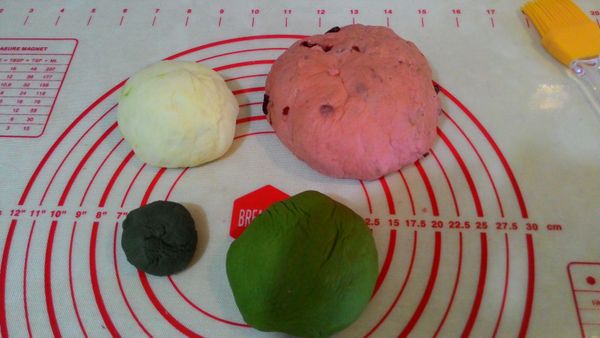 粉紅色麵團麵包機完成時，大概白色. 綠色.墨綠色的麵糰也差不多完全第一次發酵，再來就是要做組合整型 ，紅色揉成長方體狀是在最裡面，外層包上白色麵糰，請確實包緊，(不然烤出來會分離，我的就有....)再包上綠色麵糰也一樣包緊，最後將墨綠色麵糰分成12細條，一條條粘在綠色麵糰外面(粘不住可以沾一點點水)