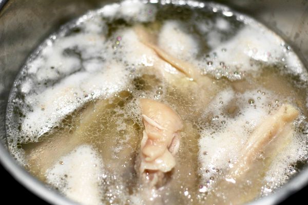 待血水浮末煮出之後，沖冷水將雞肉洗乾淨。