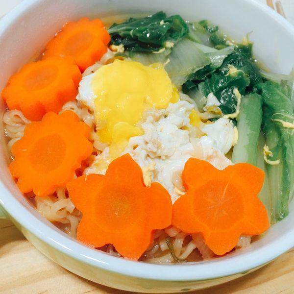 將麵放入碗中，再將紅蘿蔔片、小白菜、雞蛋依序擺盤