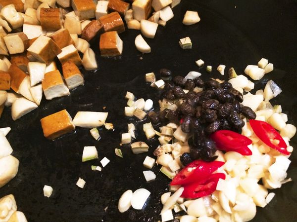 1.把炒過的食材移動到鍋子的一角2.加入1小匙油爆香豆鼓，辣椒，薑末，蒜末