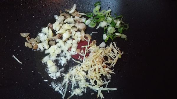 起油鍋，下蔥白、薑絲、蒜末爆香。