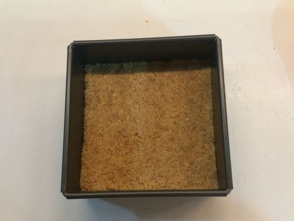 將基底的奶油和糖隔水加熱融化後，加入用桿麵棍壓碎的威化餅，攪拌均勻，鋪在蛋糕盆底部壓緊，放入冰箱冷藏。