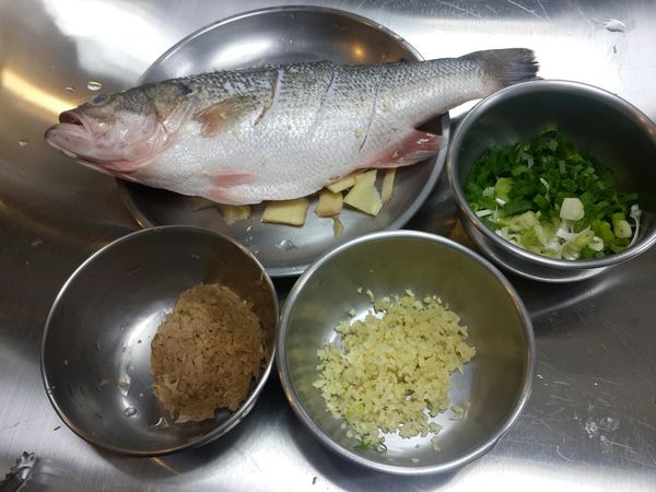 金目鱸魚洗淨, 需清洗肚內內臟及魚鰓內, 魚身上兩面各劃三刀, 冬菜用清水洗淨擰乾, 薑切細末, 蔥切細末備用. (先燒一鍋熱水, 抓住魚尾,將整條魚過一下滾水, 這個步驟是去除魚腥雜味)