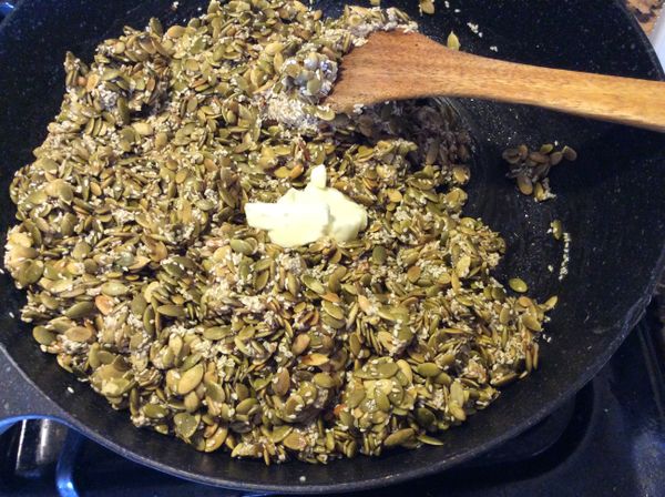 快速從烤箱取出南瓜子及芝麻倒入，並加入奶油翻拌均勻。