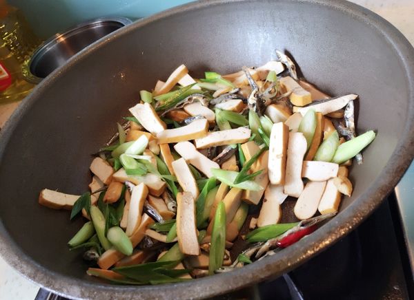 熱油鍋爆香蒜頭、辣椒，依序放入小魚乾、豆干拌炒，加點醬油再放入蒜苗繼續拌炒。