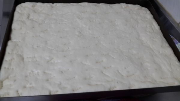 將麵團用桿麵棍桿開成烤盤大小的長方型，放上烤盤後慢慢再整形至麵皮厚薄度一致,噴水保濕發酵約50分鐘