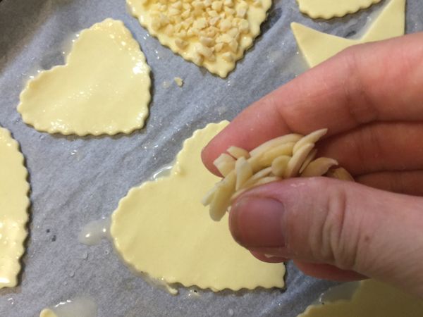 將杏仁粒、杏仁角撒到步驟2的酥皮上，用手指輕微的加壓一下，讓杏仁跟餅皮多一些黏著度