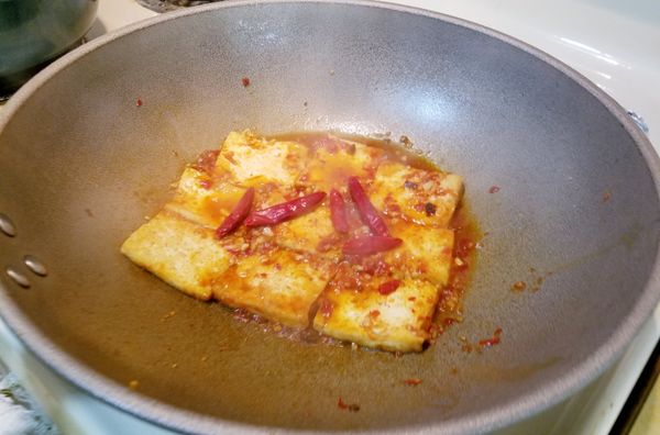 加入半碗的水，把乾辣椒及少許的冰糖放入煨煮一下。