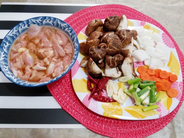 將雞肉切塊以1顆蛋白、1匙醬油、1匙米酒、少許的胡椒粉及香油醃約20分鐘，之後再加入1匙的太白粉拌均；蒜頭切片、洋蔥切段、香菇去蒂頭後對切、紅蘿蔔切片、青蔥切段備用。