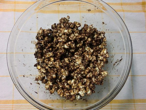 在一個大的攪拌盆裡倒入50克爆好的爆米花，再將煮好的可可糖漿均勻淋在表面，趁熱快速翻拌均勻。