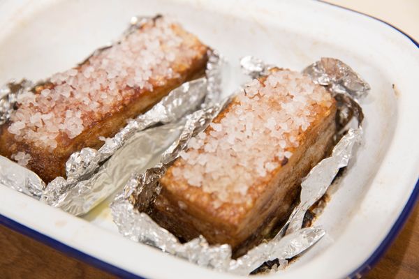 把粗鹽鋪滿豬皮這可以吸收烤出來的水分,導熱也會平均,更可以增加一點點鹹味.不可以用平常的細鹽喔!細鹽烤過會整個融化在豬皮上,之後無法撥掉也會太鹹.
將豬五花送入預熱220度的烤箱烤30分鐘拿出,將粗鹽拿出此時鋁箔紙裡已經烤出一些豬油若太多可以先倒出,再放回烤箱溫度調低至200度放在烤箱上烤20分鐘