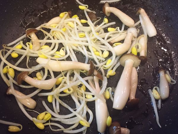 將鴻禧菇和豆芽菜炒至半熟後倒至盤子。