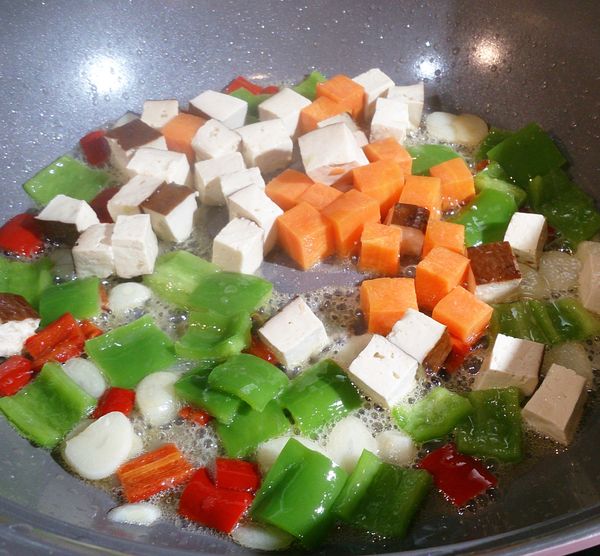 先放入胡蘿蔔炒至半熟後，再加入豆丁及青椒等一起拌炒