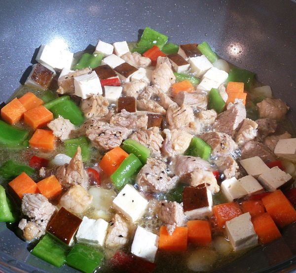 再加入肉丁拌炒至半熟加入水，當水滾後加入鹽快速拌炒