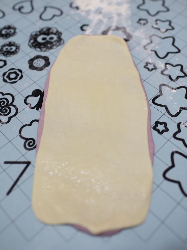 把桿平的紫薯麵糰刷上一點油(這裡用橄欖油)再把牛奶麵糰疊上去，稍微桿一下在桿平的牛奶麵糰上刷一點油。