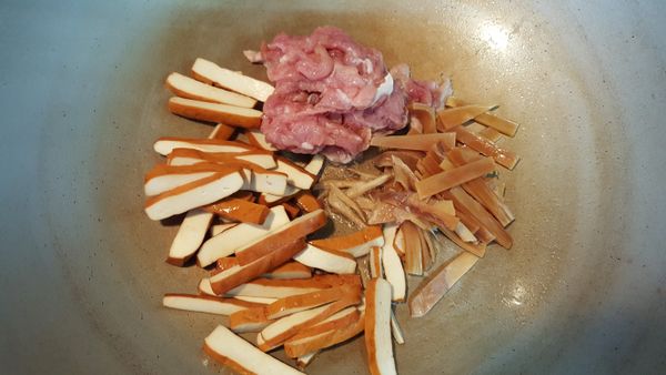 鍋中加入適量的油,放入薑絲肉絲,豆干絲,魷魚絲略煸至金黃色後
加入蒜片續炒片刻