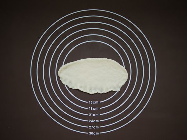 將鬆弛後的8個46g大麵團擀成橢圓形，翻面後壓薄底邊。