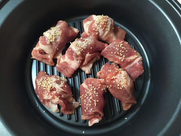 將包好的豬肉捲放入煎烤盤（烤盤不用抹油），撒上白芝麻在肉捲上