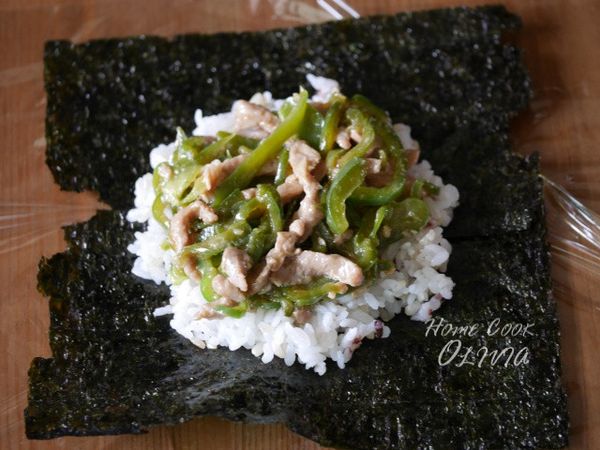 桌面墊保鮮膜，依序放上海苔、白飯、餡料、白飯，