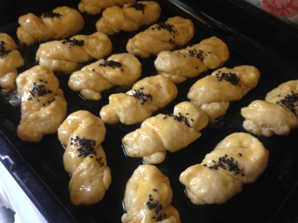 烤盤上倒1T沙拉油抹好，把麻花卷一個一個放好如圖，最後塗上蛋黃，撒上黑芝麻如圖，放入預熱好的烤箱，180度，中下層，烤大約25-30分鐘，直到表面有些焦黃即可。