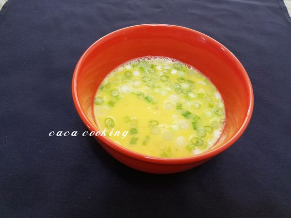 蛋液加入許少的鹽、1匙的薄鹽醬油、3匙的冷開水、1匙的太白粉、少許的香油攪拌，之後再加入干貝及青蔥拌勻。