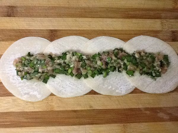 5.玫瑰造型的包法:5b.取適量的[內餡食材]於一字型餃子皮的中間。