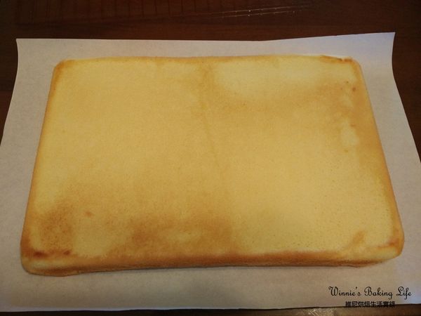 待蛋糕片稍涼後，撕取一張新的白報紙，覆蓋在表面，並翻面將底部白報紙撕開

(將金黃烤面捲在外側)