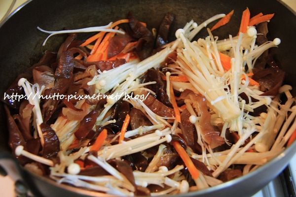 放入醬油、黑木耳絲和金針菇，拌炒一下後，蓋上蓋子悶一下。