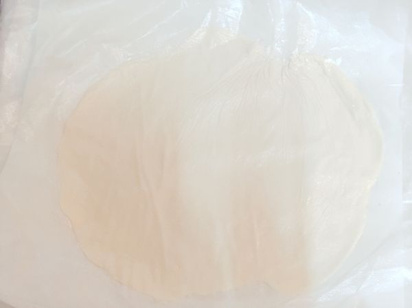 最後，拿出一張保鮮膜或是烘焙紙鋪在桌面上，抹上少許的油在上面，拿出一顆麵團放在保鮮膜上，麵團也要抹上少許的油，之後再鋪上一張保鮮膜或是烘焙紙，然後開始用手壓讓麵團變成一張餅皮，如果習慣用桿麵棍的人也可以用桿麵棍，如果沒有桿麵棍也可以用瓶子或手用。