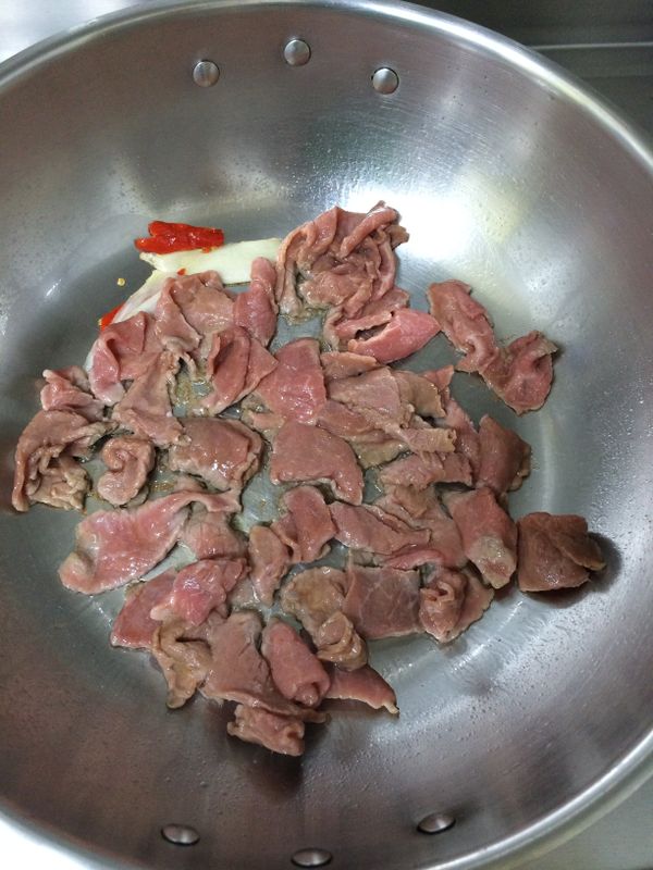 將牛肉片放入鍋中，中火炒至肉變色後呈起備用。