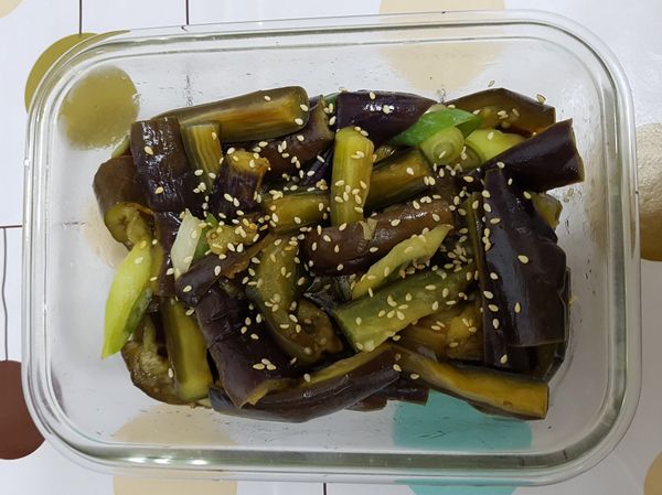 這時再把剛剛切好的蔥花放入，調味料（日式醬油、芝麻油、糖、塩放入）適當的攪拌一下，待攪拌差不多的時候，再灑上一些白芝麻粒，增色又提味，此時先靜置一段時間，茄子會再慢慢釋出水份，此時再與調味料融合後，味道會更好