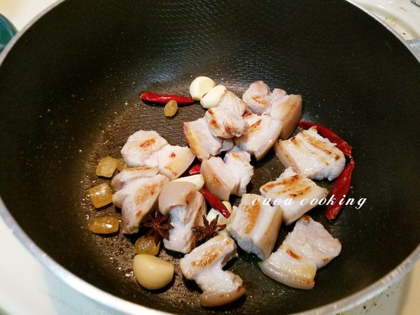 把蒜頭、乾辣椒、八角、冰糖下鍋，與五花肉一起炒香。