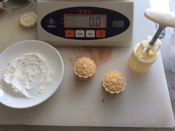 皮與餡的比例為2:3，我的餅模為50g，所以用20g的皮，30g的餡，秤好分量，餅皮用掌心按扁，包入餡料，將餅皮慢慢推開，完全包覆餡料。準備一些熟的糯米粉，包好的餅沾上熟粉，放入餅模，壓製成型。