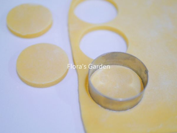 桌面和麵團表面都撒些手粉、擀成一公分厚，用圓模(直徑約5公分)壓出圓片。