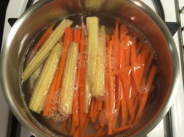 玉米筍切對半、紅蘿蔔切絲，較硬的食材稍微川燙過，等會進烤箱較快熟透。