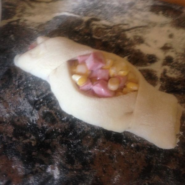 就像穿浴袍一樣，左邊包過來右邊包過去，再把兩邊都塞到下面，把麵團整成如圖一般，中間大，兩邊小的形狀。