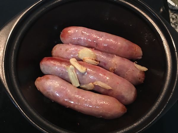 放入香腸略煎上色後取出，關火。煎香腸的同時可陸續將蒜片夾起放在洗好的糙米上以免焦掉。