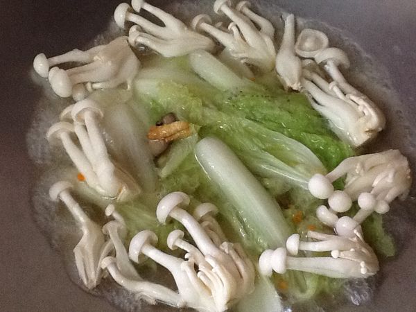 16.再倒入蒸熟豆腐鑲肉的湯汁，放入娃娃菜、美白菇及少許的水煮滾。