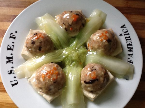 19.把步驟12. 完成的[豆腐鑲肉]擺入盤中，擺上娃娃菜。