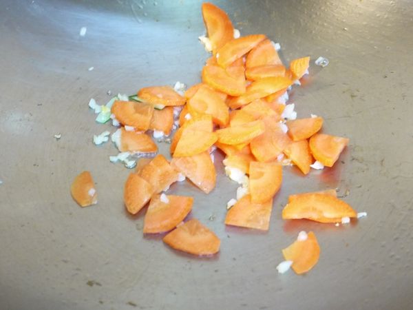 同一鍋，再加入一大匙油加熱後，先放入蒜碎炒香，再放入紅蘿蔔片炒到稍微變軟。