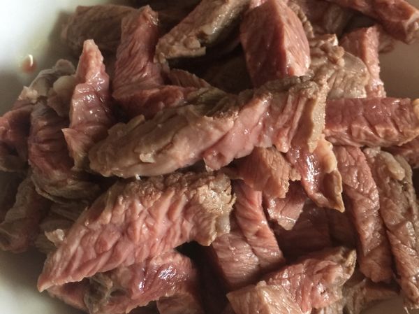 將牛肉切成約一公分厚的長條。
熱鍋倒入約兩鏟匙的油，將牛肉入鍋煸炒一下約5分鐘後起鍋