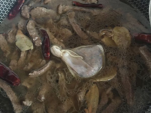 香味出來後放入煸炒過的牛肉、醬油、米酒、糖（醬料2），拌炒一下再倒入約500cc的水，放入滷包大火滾了以後轉小火煮30分鐘